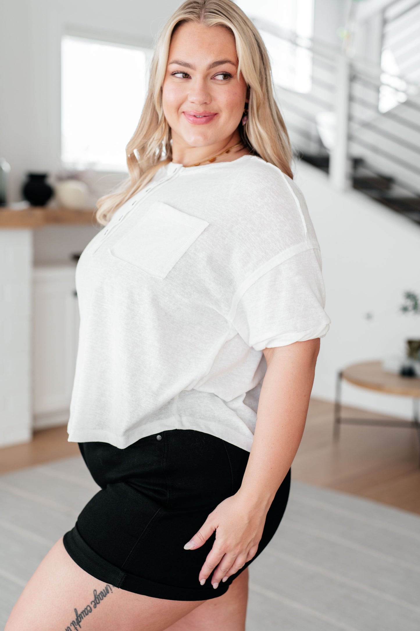 Woman wearing a white top and black shorts in a modern indoor setting