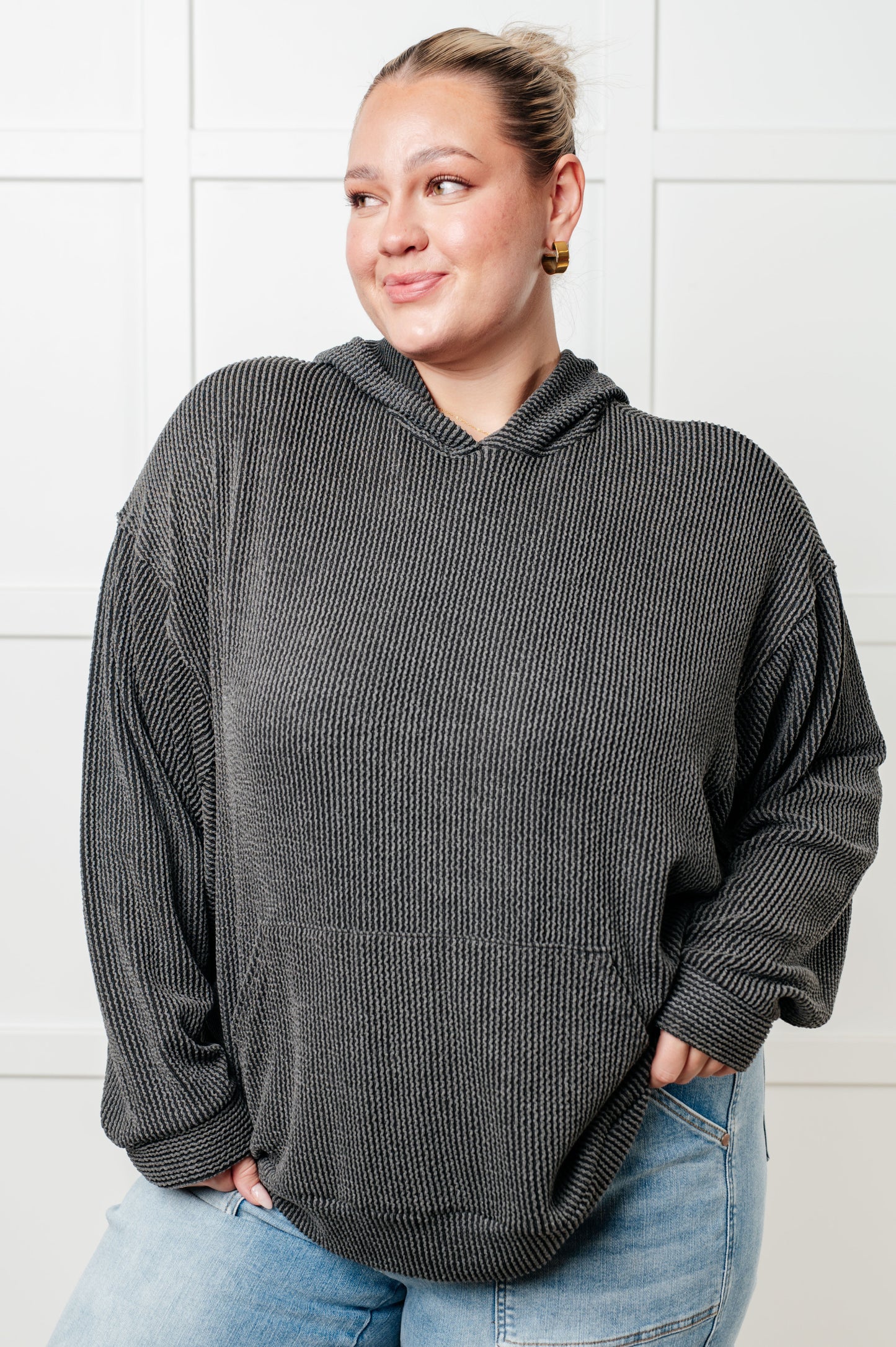 Woman wearing a gray oversized hoodie against a white background