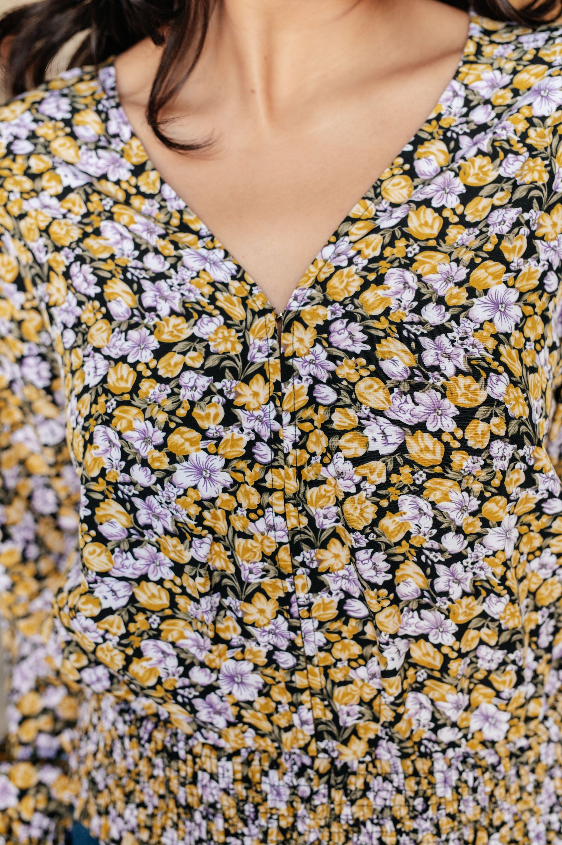 Close-up of a floral-patterned garment with yellow, purple, and black colors.