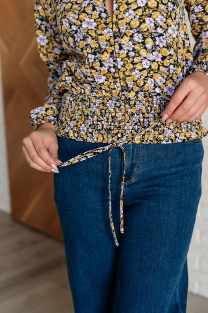 Person wearing a floral top and blue jeans with a blurred background