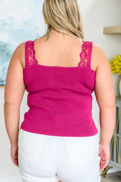 A woman wearing a berry-colored, lace-trimmed sleeveless tank top with a v-neckline, paired with white shorts.