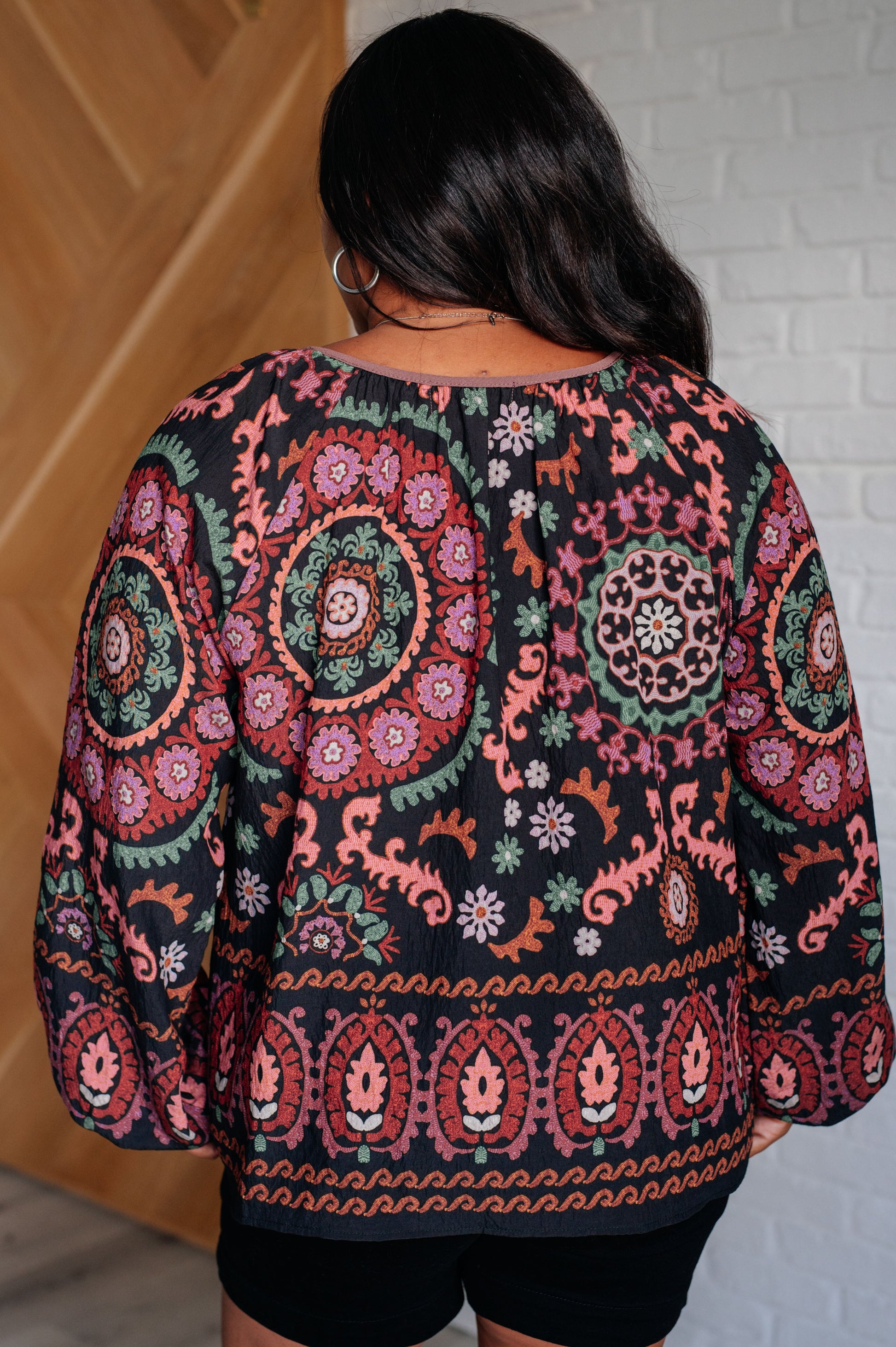 Person wearing a patterned sweater with a white brick wall background