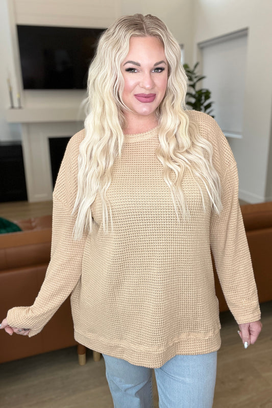 Woman wearing a beige sweater in a living room setting