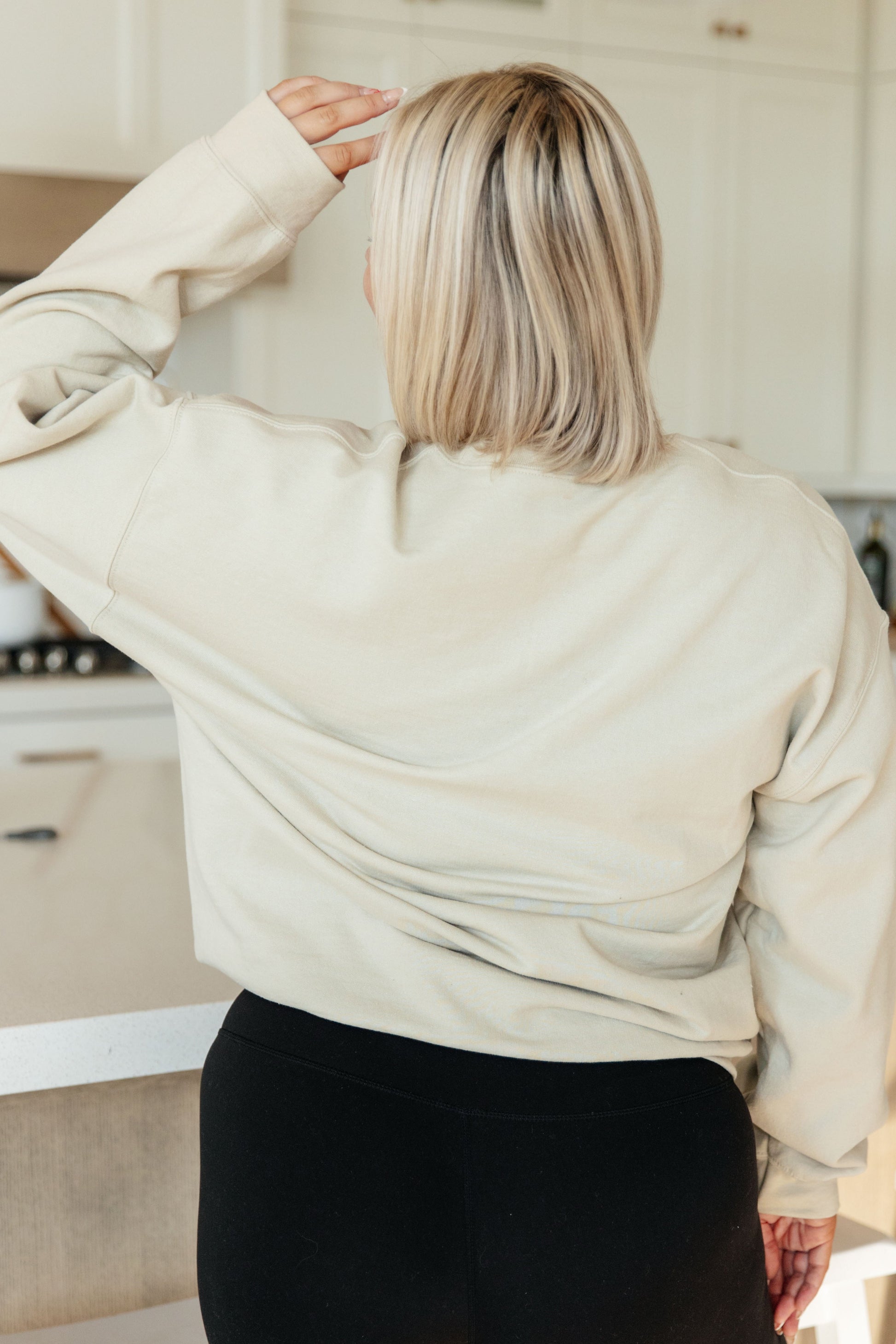Person wearing a beige hoodie in a kitchen setting
