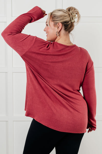 Person wearing a red long-sleeve top against a white tiled wall