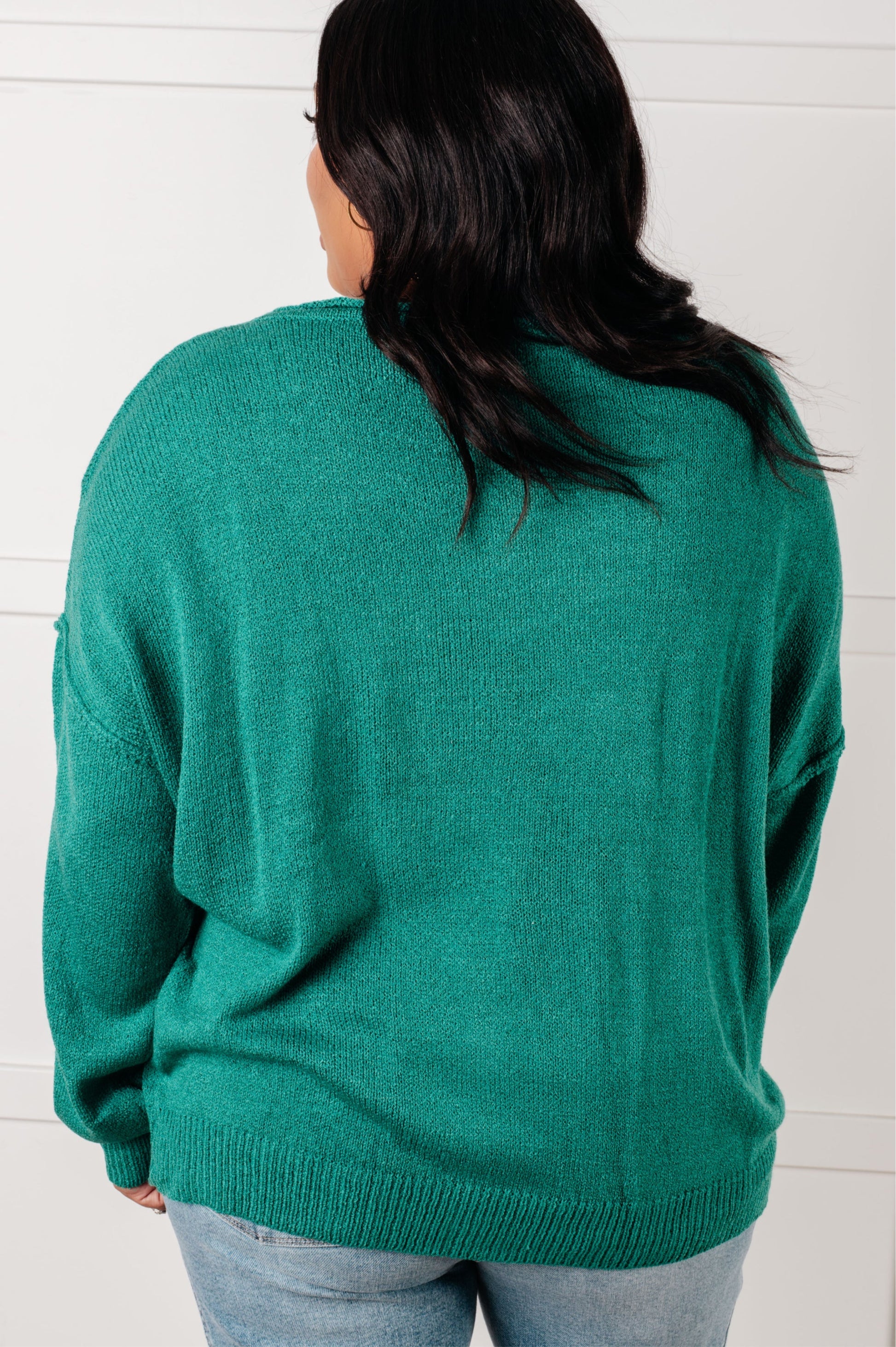 Person wearing a teal sweater against a white background