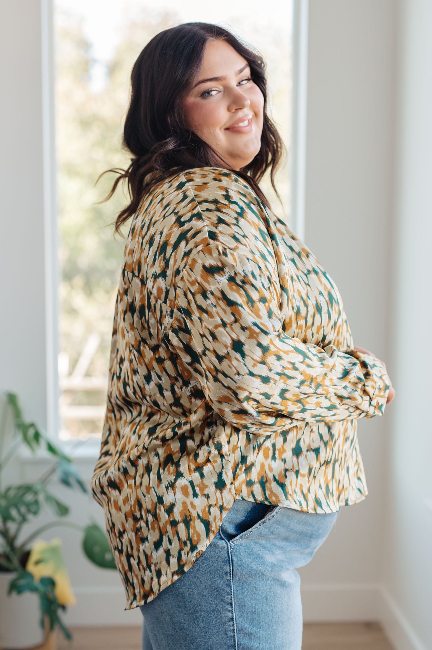 Woman wearing a patterned blouse and jeans indoors