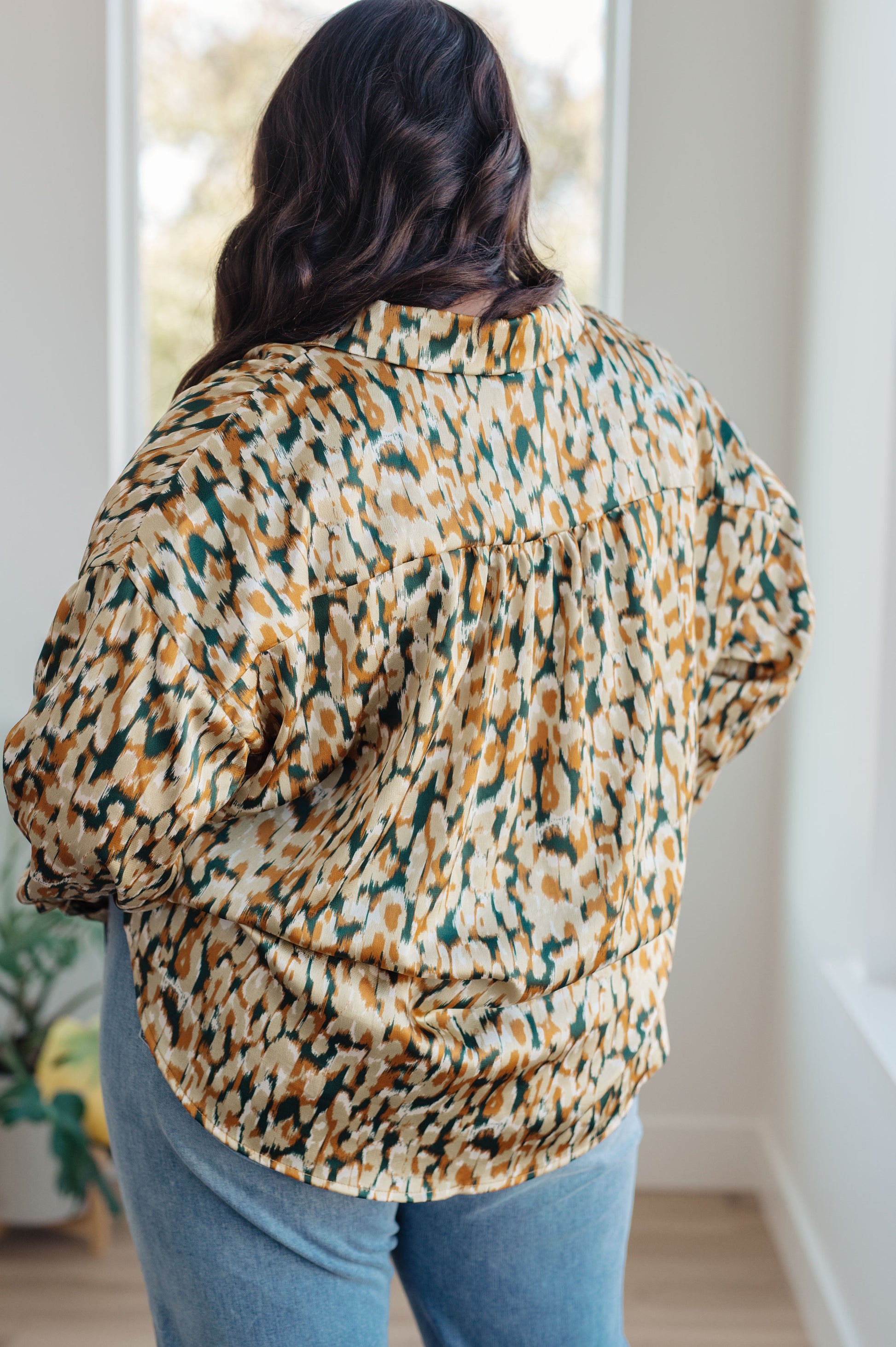 Person wearing a patterned shirt and jeans indoors