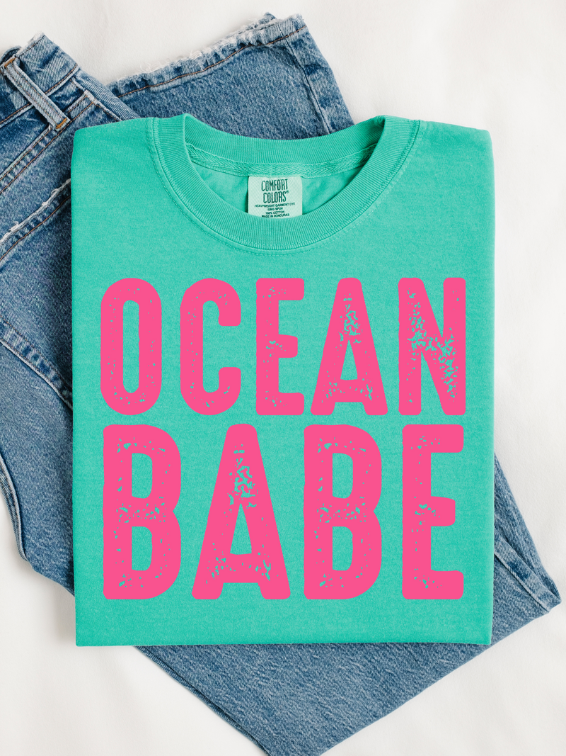 Green t-shirt with 'Ocean Babe' in pink text on a white background