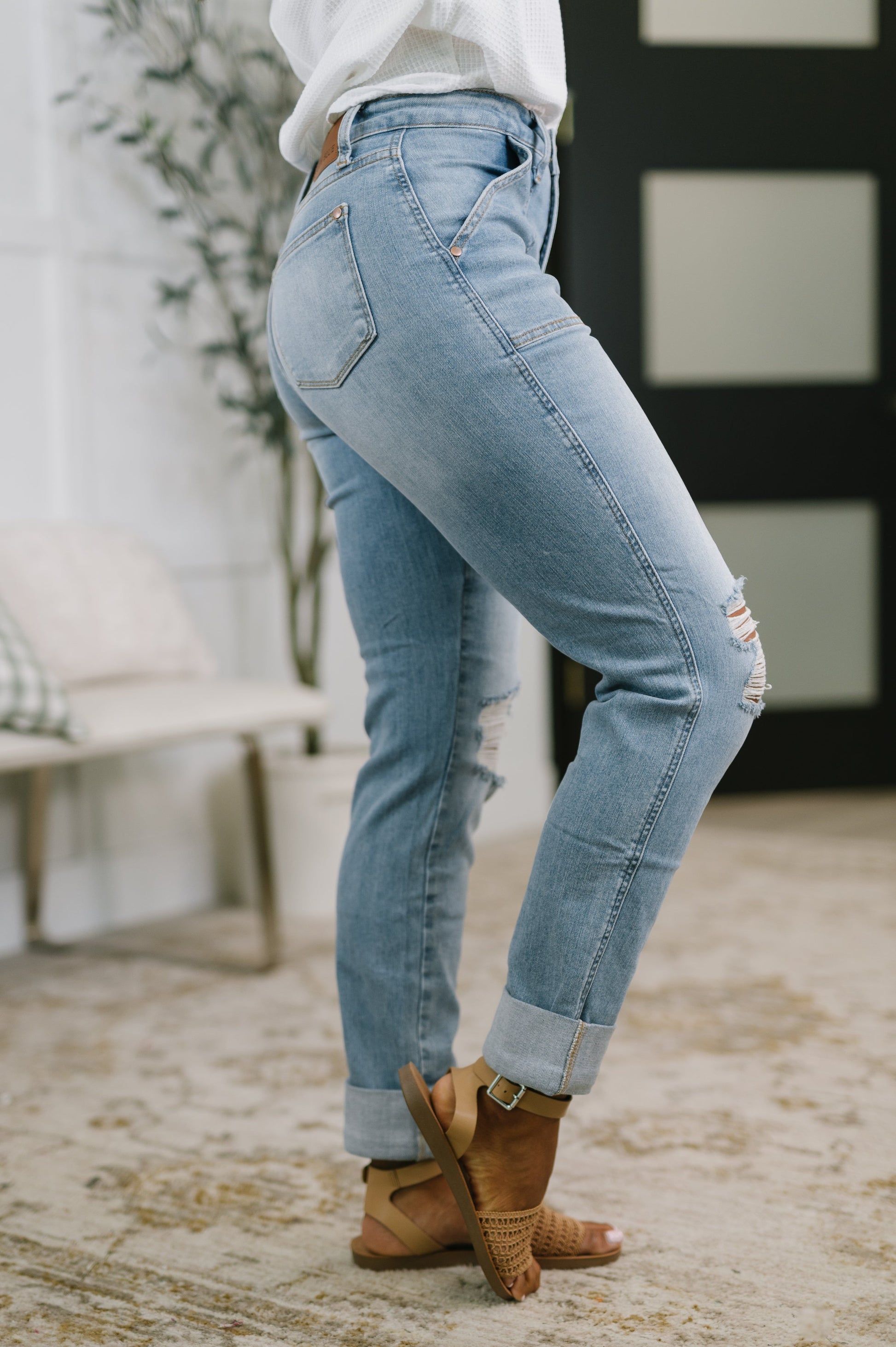 Person wearing light blue jeans and brown boots standing on a stone surface.
