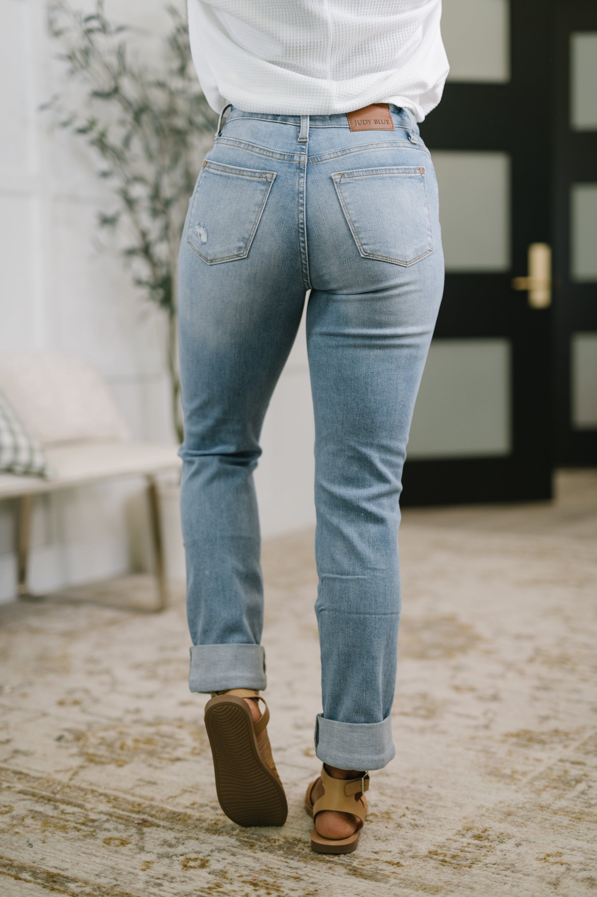 Person wearing light blue jeans and brown shoes indoors.