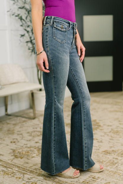Person wearing blue flared jeans and a purple top in an indoor setting.