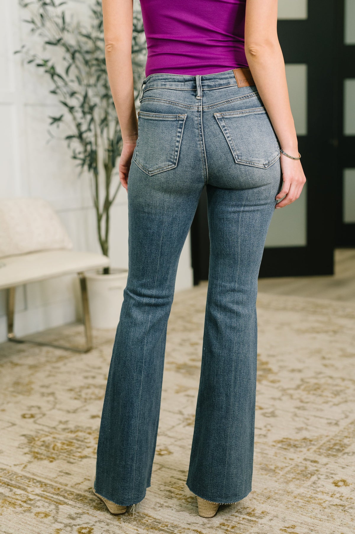 Person wearing blue jeans and a purple top in an indoor setting