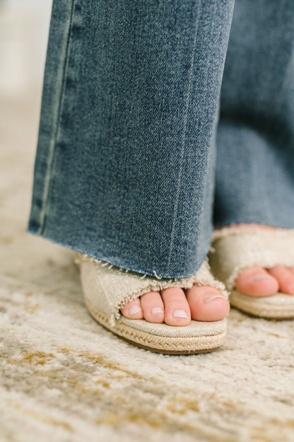 Close-up of feet wearing sandals with blue jeans on a textured surface