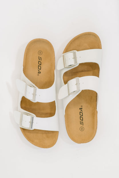 White sandals with brown soles on a white background