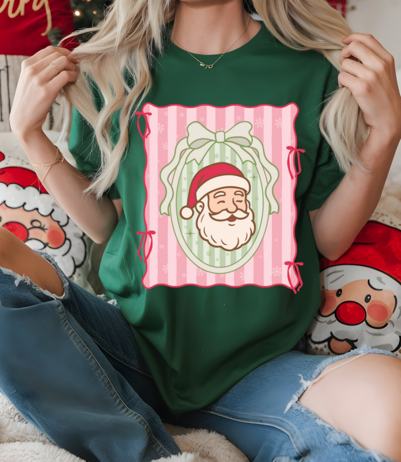 Person wearing a green t-shirt with a festive design of Santa Claus in a mirror, sitting on a couch with Christmas-themed pillows.