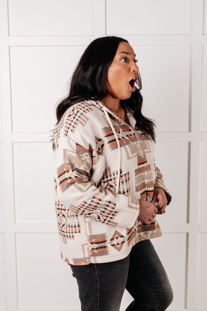 Woman wearing a patterned hoodie against a white tiled wall
