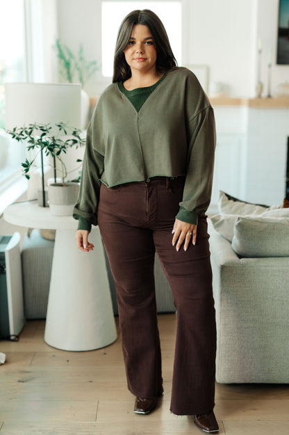 Woman wearing a green cardigan and brown pants in a living room setting