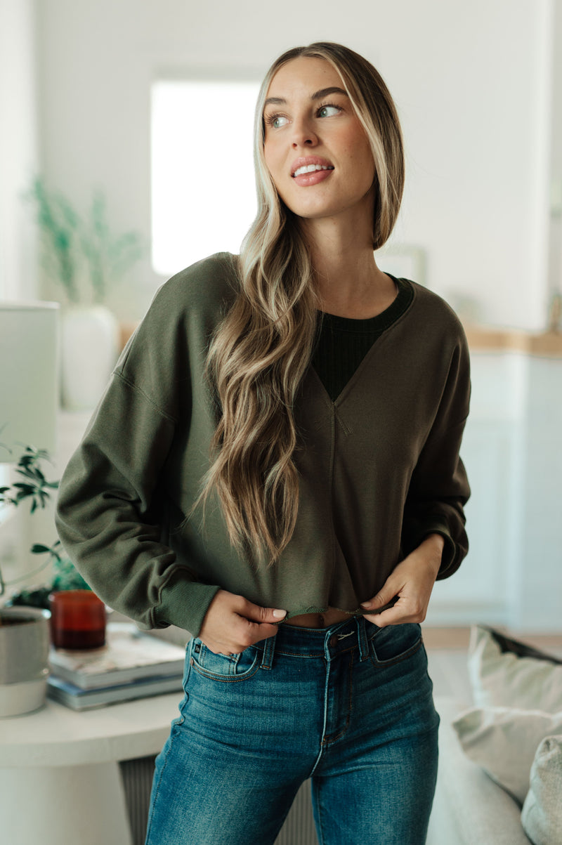 Woman wearing a green sweater and blue jeans in a bright room.