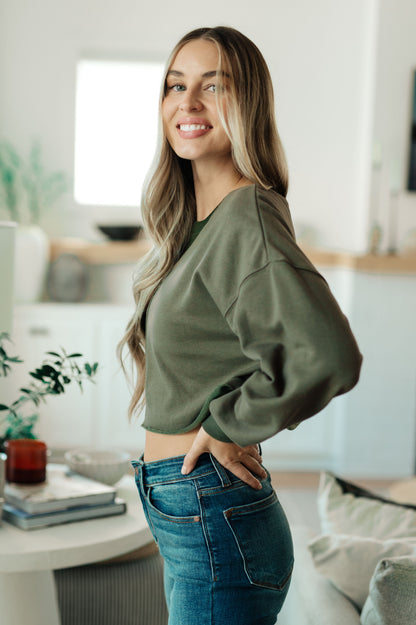 Woman wearing a green sweater and blue jeans in a modern living room.