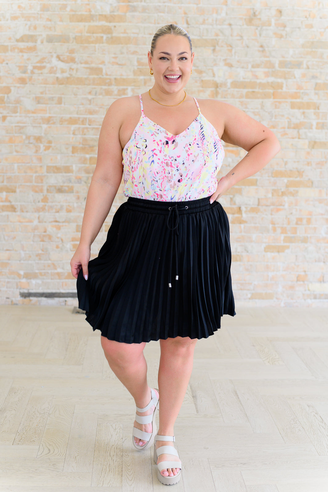 A woman wearing a multicolor printed camisole top with a v-neckline and adjustable straps, paired with skirt.