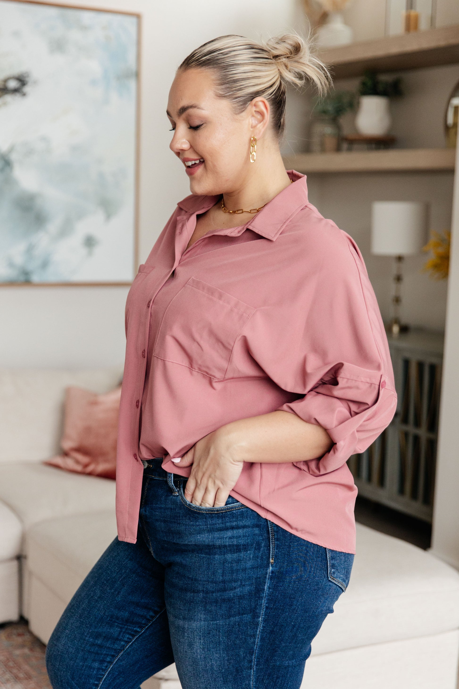 Woman wearing a pink shirt and blue jeans in a living room setting