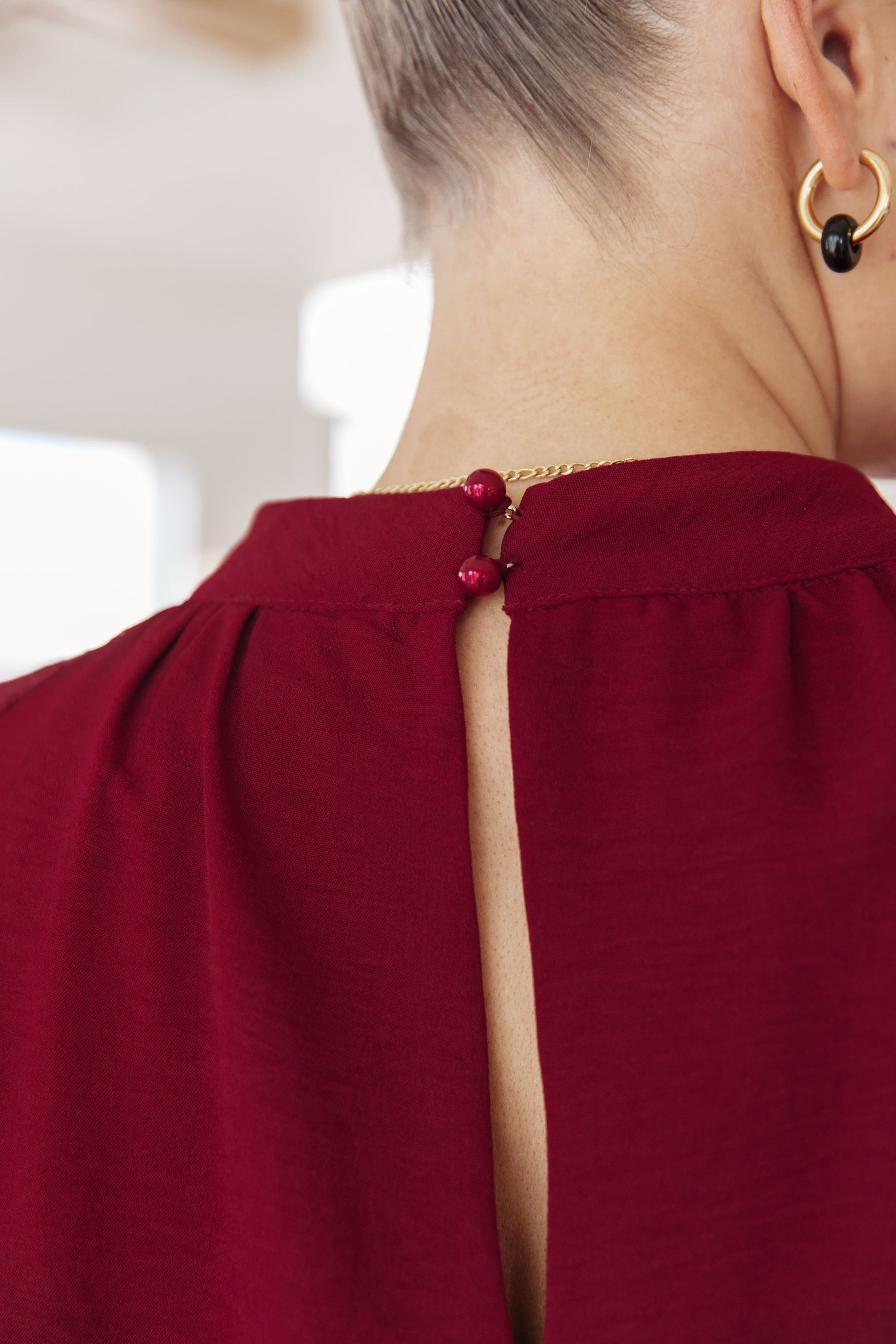 Close-up of a person wearing a burgundy top with a cut-out design, focusing on the neckline.