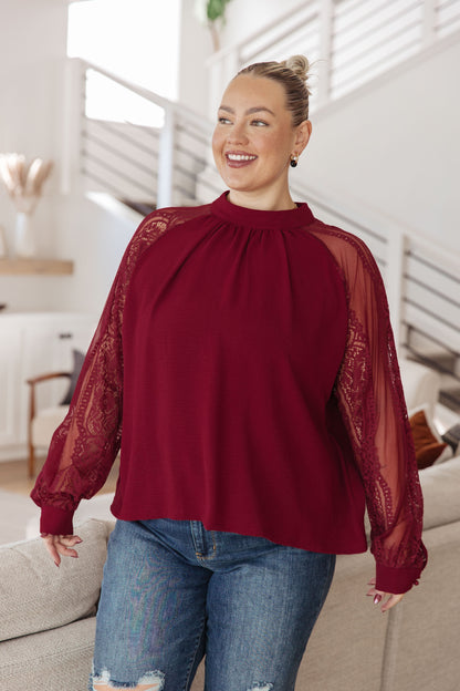 Woman wearing a burgundy blouse with sheer sleeves in a living room setting