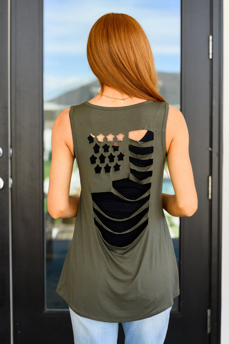 A woman wearing an olive green tank top with a laser cut flag design on the back, in a v-neckline cut.