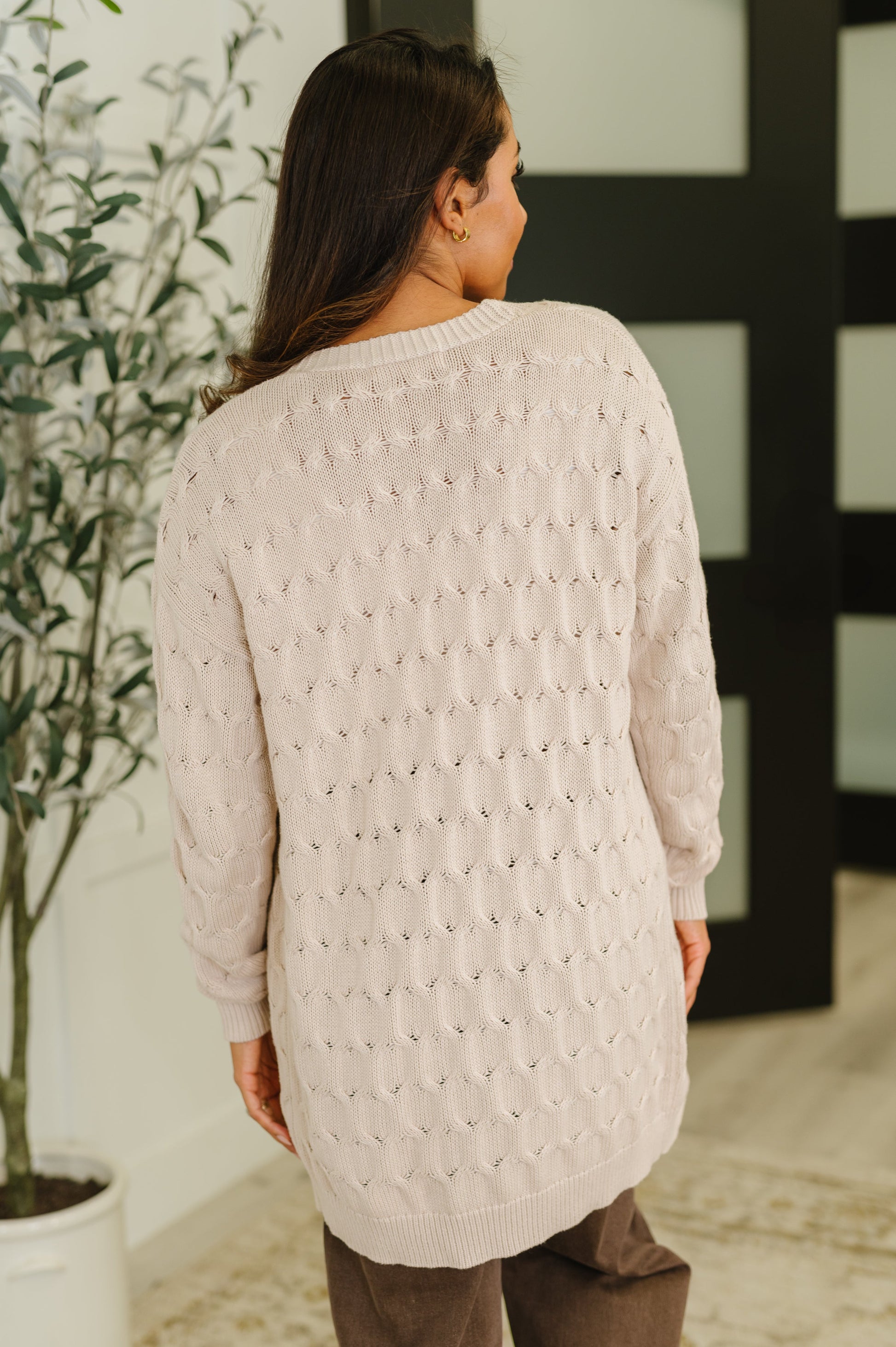 Person wearing a light pink textured sweater in an indoor setting