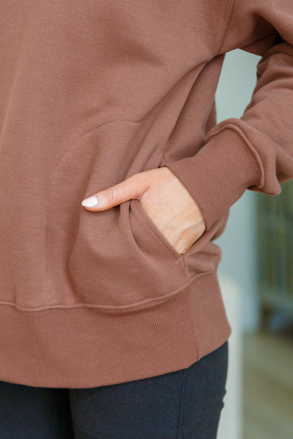 Brown sweatshirt with a pocket, worn by a person.