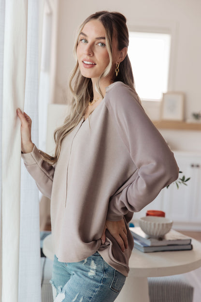 Woman wearing a beige blouse and blue jeans in a bright room.