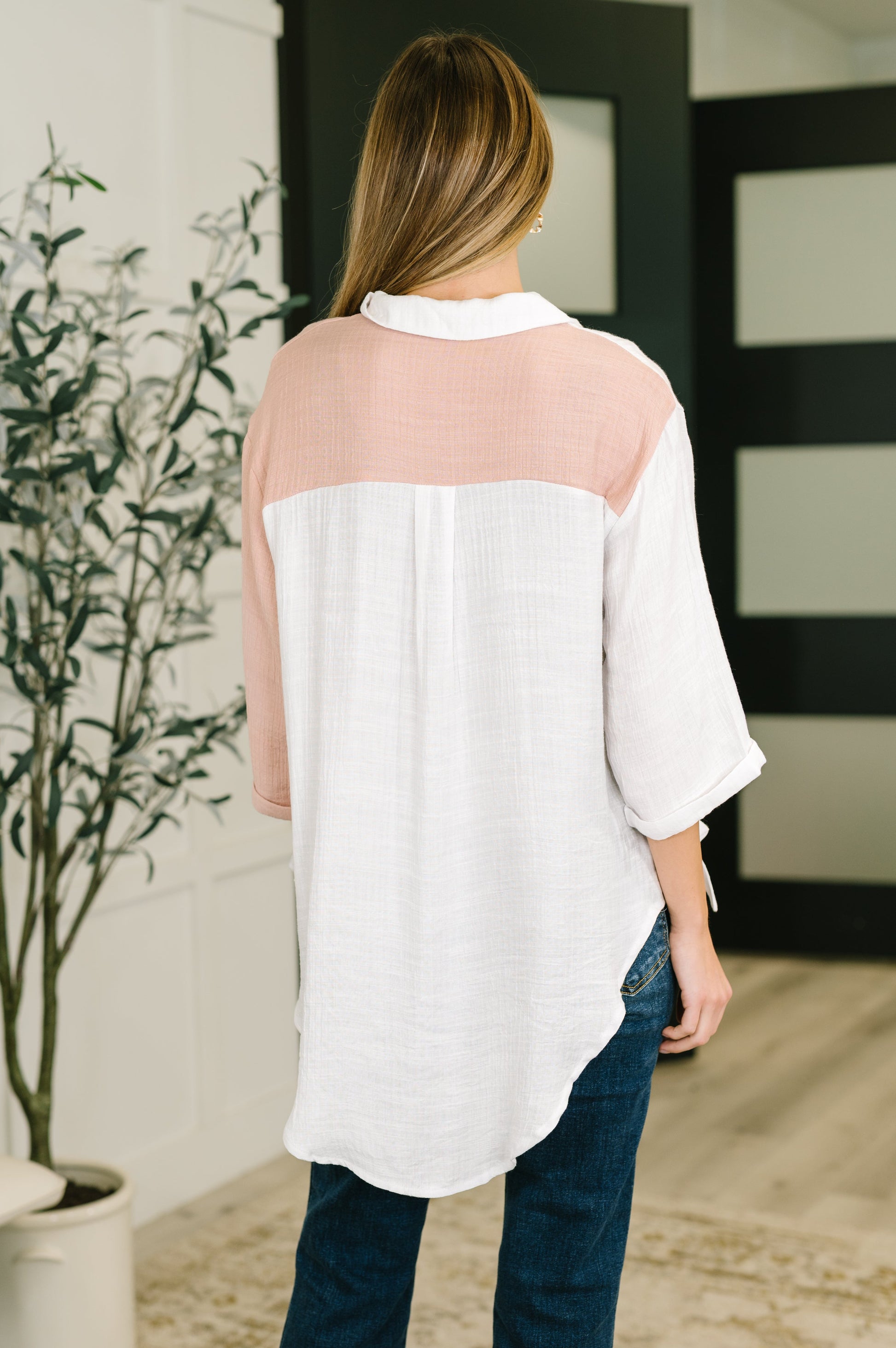Woman wearing a white blouse with sheer sleeves in an indoor setting.