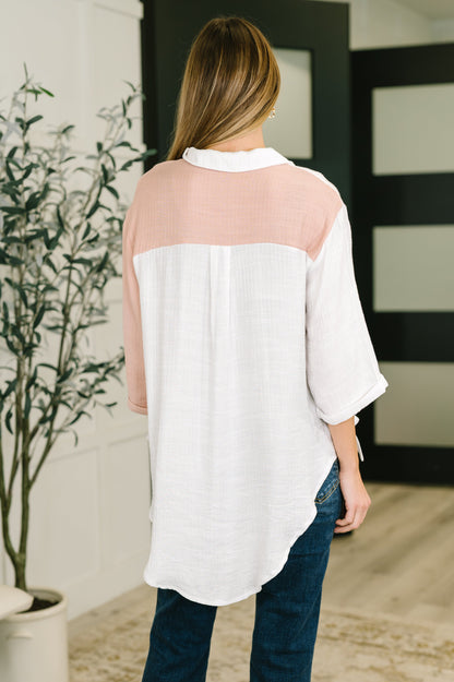 Woman wearing a white blouse with sheer sleeves in an indoor setting.