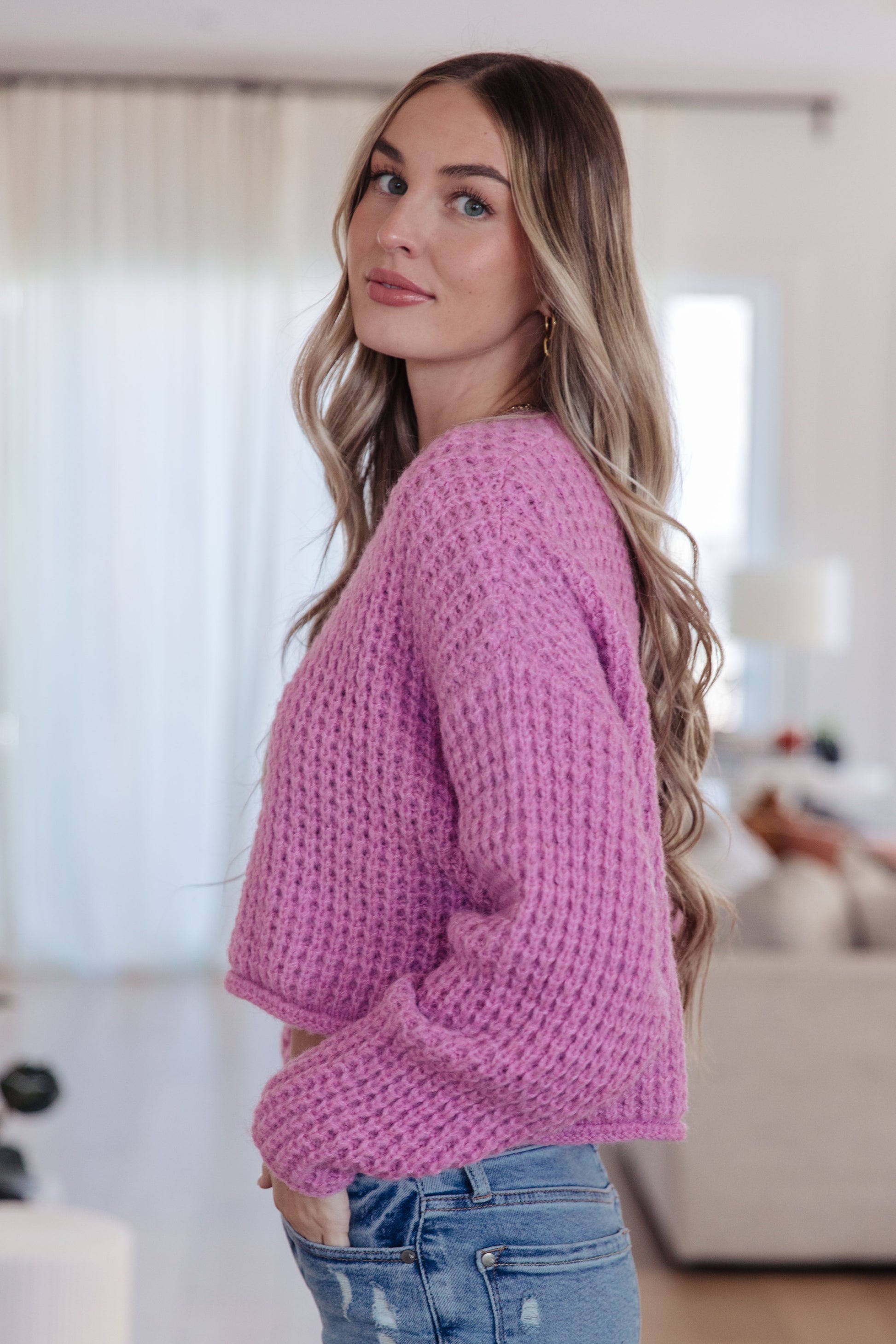 Woman wearing a pink sweater and blue jeans indoors