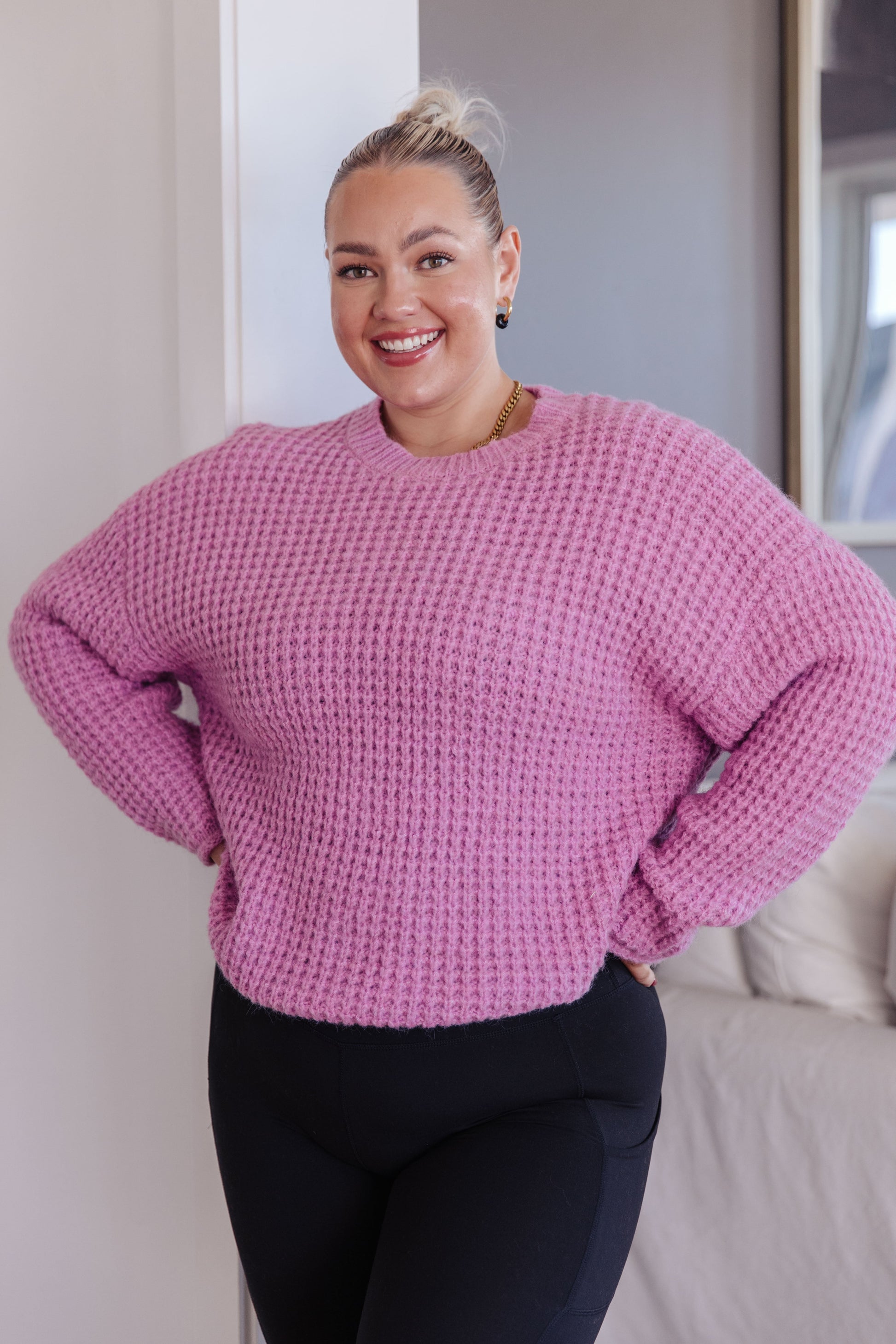 Person wearing a pink sweater standing indoors.