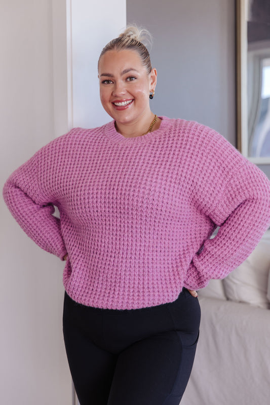 Person wearing a pink sweater standing indoors.