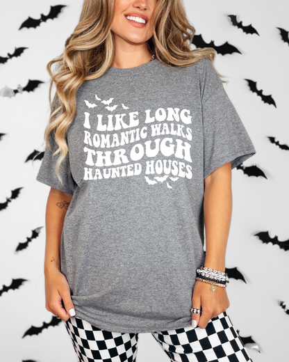 Person wearing a gray t-shirt with Halloween-themed text in front of a bat-patterned background