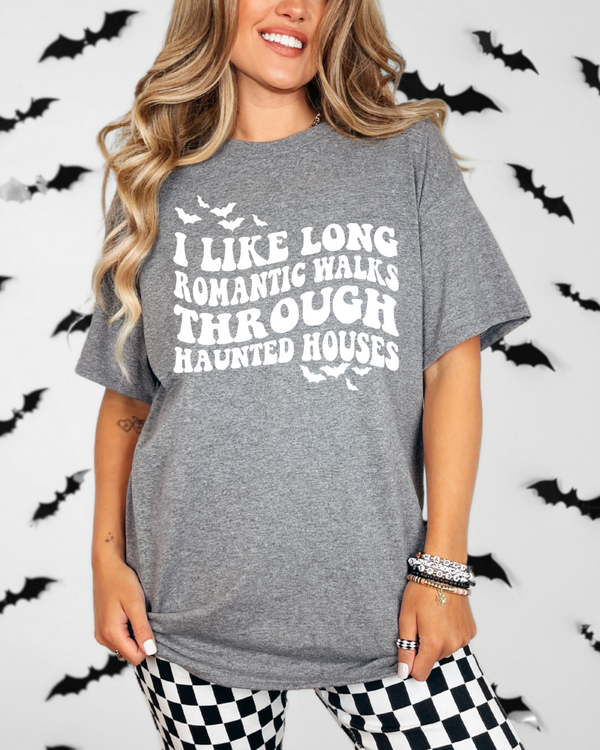 Person wearing a gray t-shirt with Halloween-themed text in front of a bat-patterned background