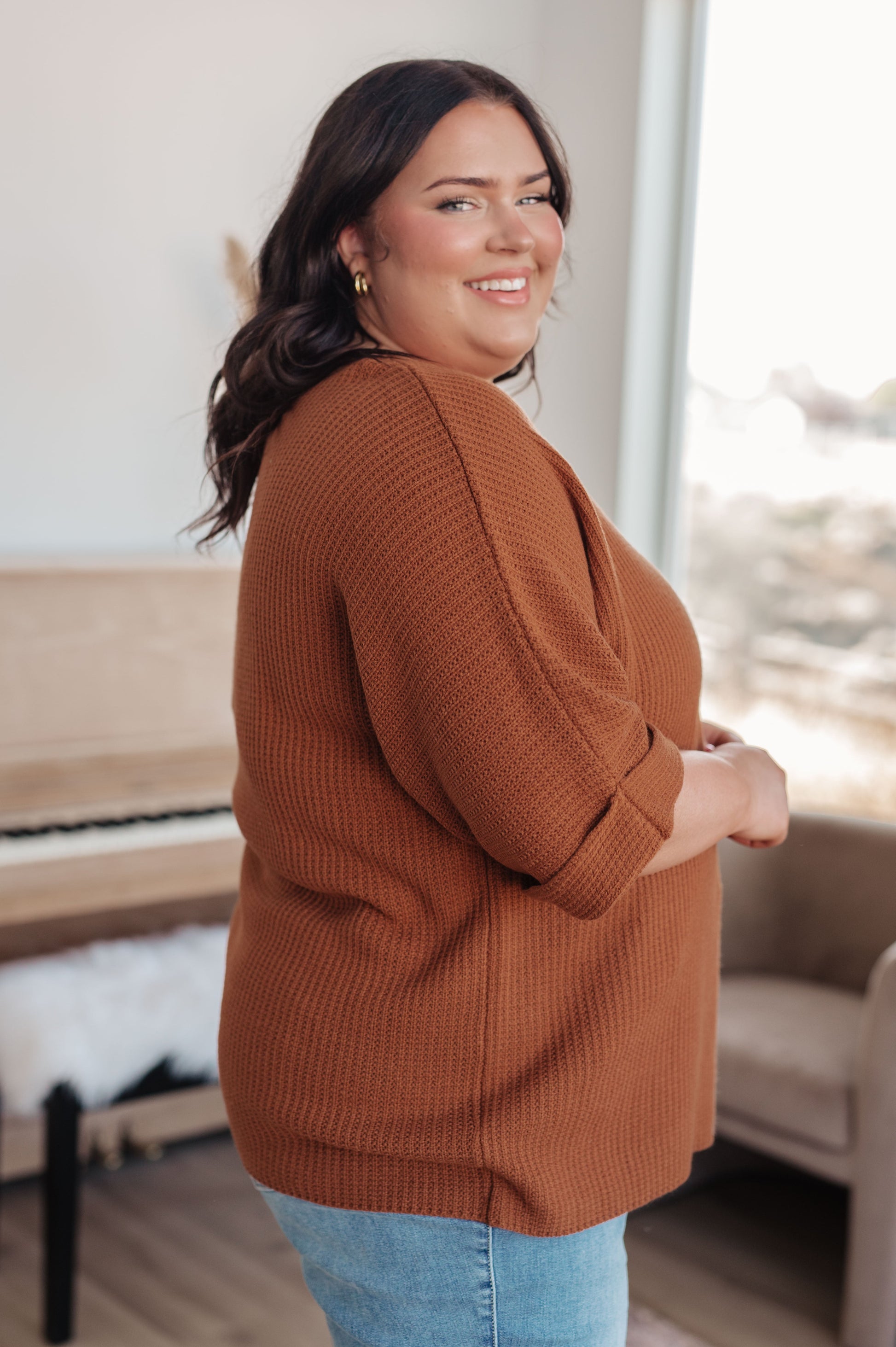 Woman wearing a brown sweater in an indoor setting