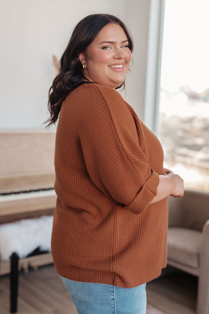 Woman wearing a brown sweater in an indoor setting