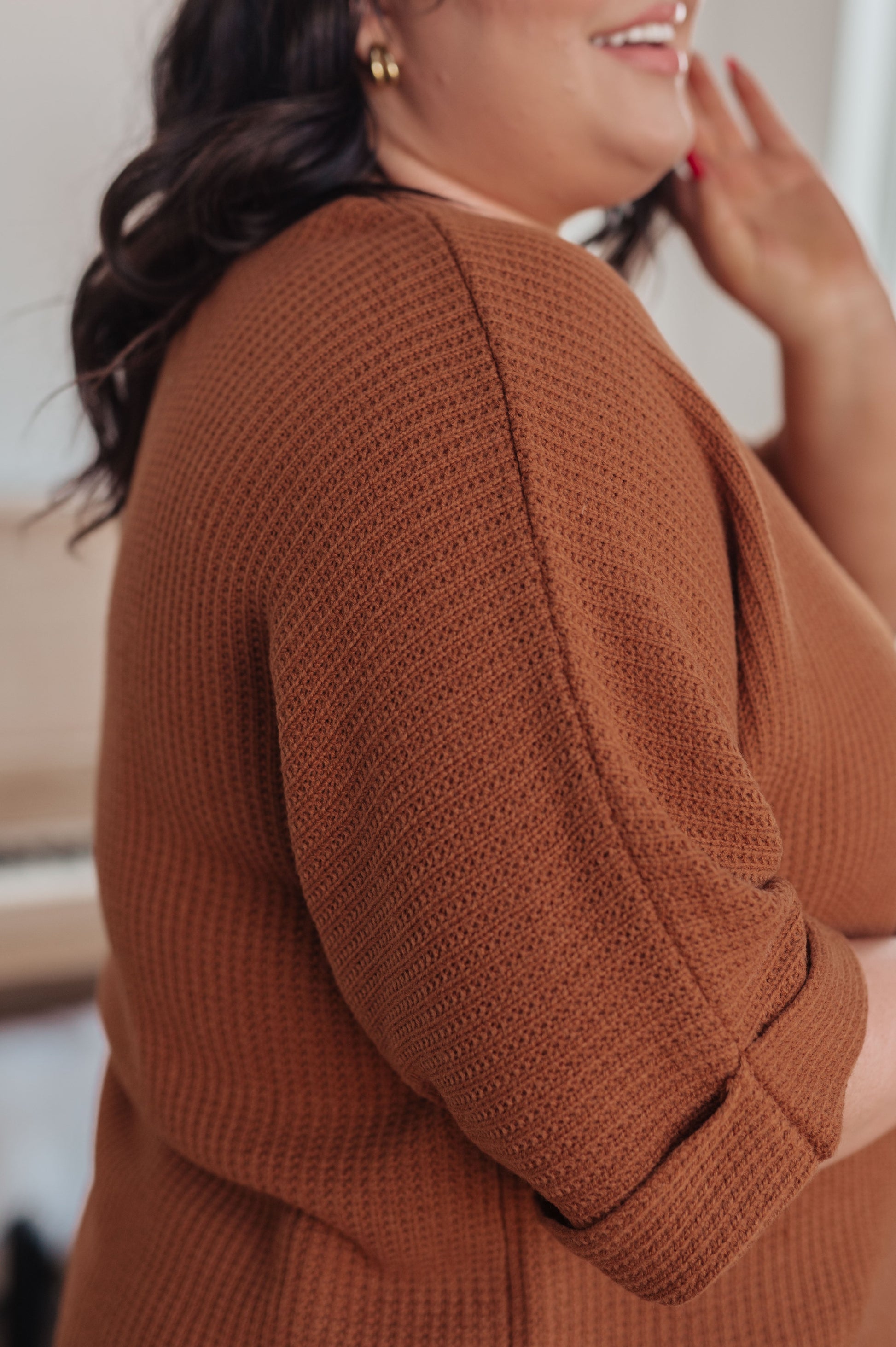 Person wearing a brown textured sweater with a blurred background