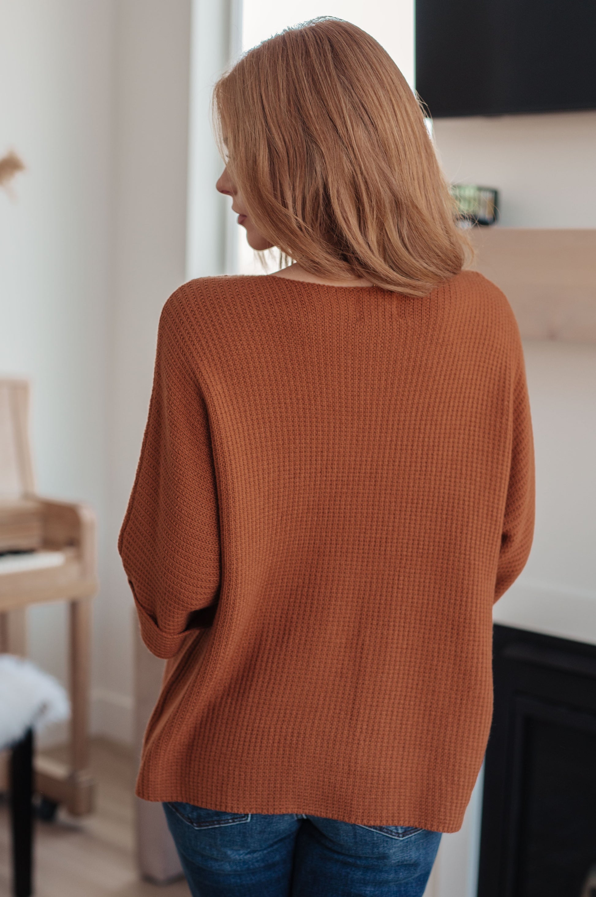 Person wearing a brown sweater in an indoor setting
