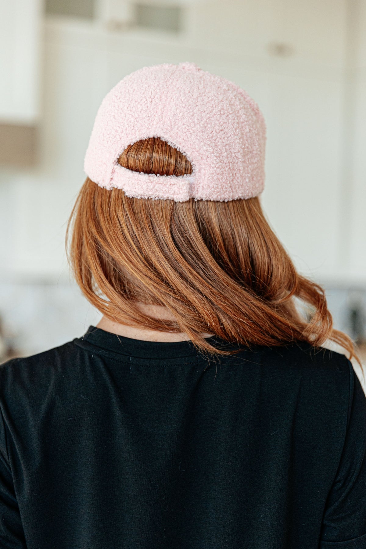 Person wearing a pink fuzzy beanie from behind in an indoor setting