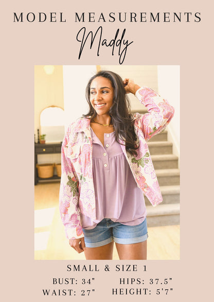 Woman wearing a pink floral jacket over a pink top and denim shorts, with model measurements displayed.