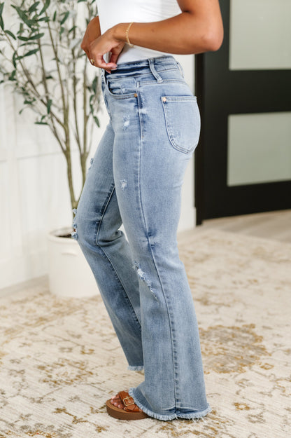Light blue jeans worn by a person indoors with a plant in the background