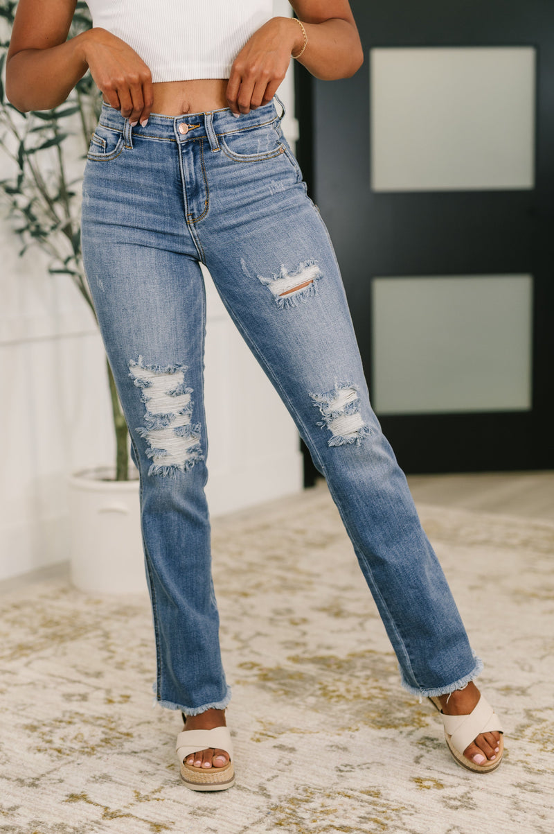 Person wearing distressed blue jeans with a blurred background