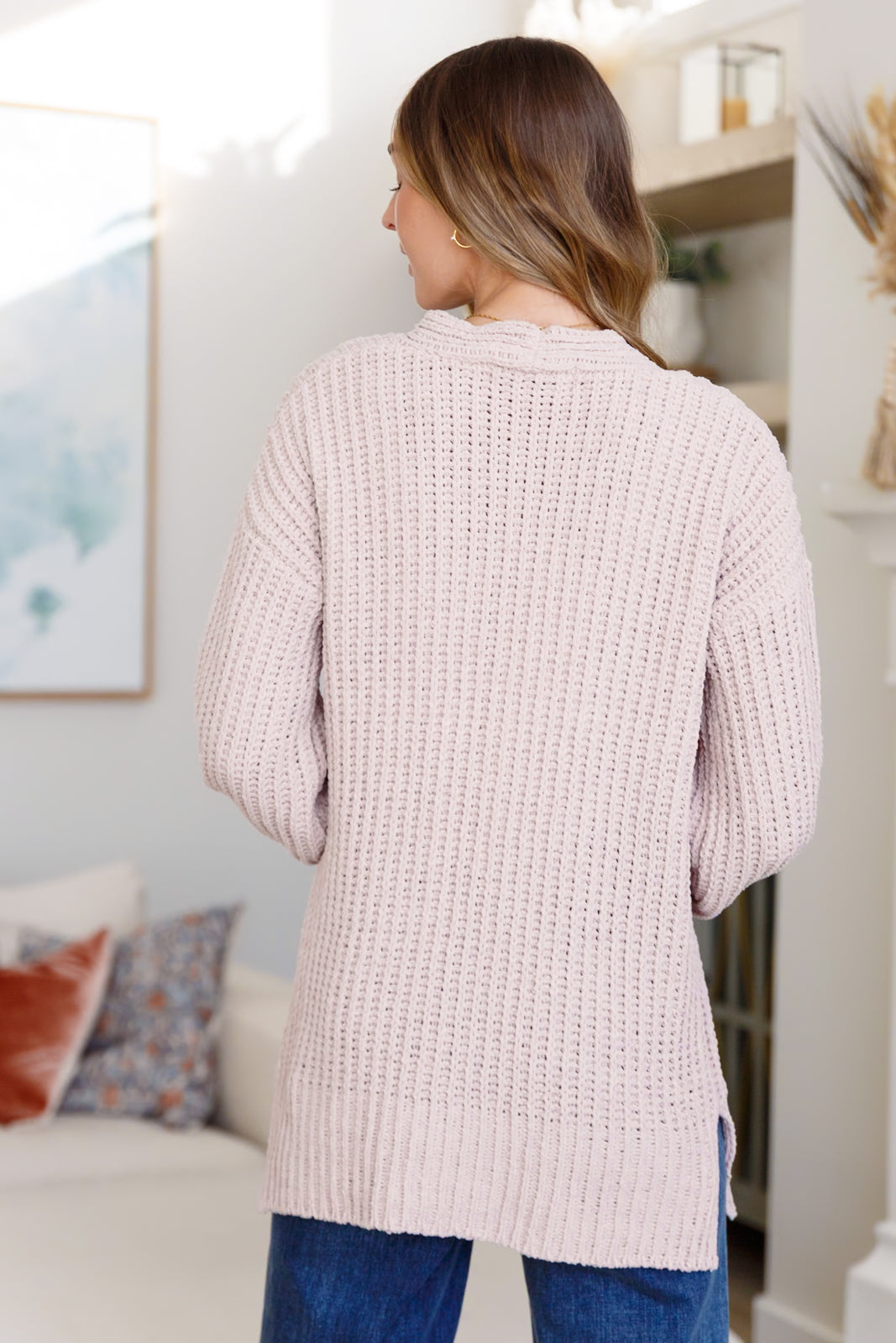 Woman wearing a light pink textured cardigan in a living room setting