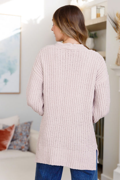 Woman wearing a light pink textured cardigan in a living room setting