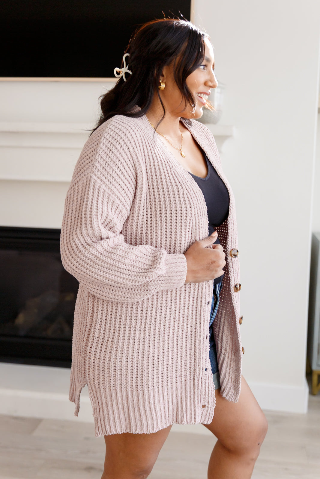 Woman wearing a long, light brown cardigan in a home setting.